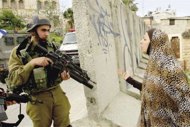 جندى إسرائيلى يصوب بندقيته باتجاه سيدة فلسطينية